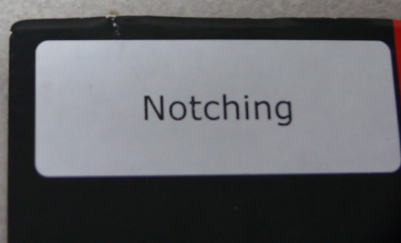 Notching example — physical sample showing a notch defect at a folding carton board edge